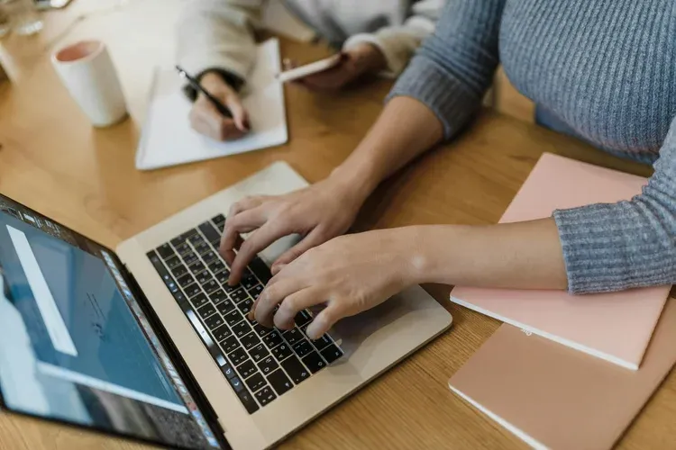 person utilizes a laptop while another takes notes